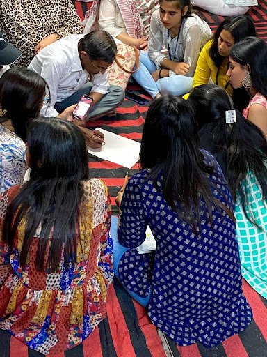Fashion textiles students from Amity School of Fashion Technology, Jaipur, discuss a traditional Gopashtami pichvai with artist Shyam Sharma and lean in to observe Parmanand Sharma sketching. 2 Fashion textiles students from Amity School of Fashion Technology, Jaipur, discuss a traditional Gopashtami pichvai with artist Shyam Sharma and lean in to observe Parmanand Sharma sketching. 2
